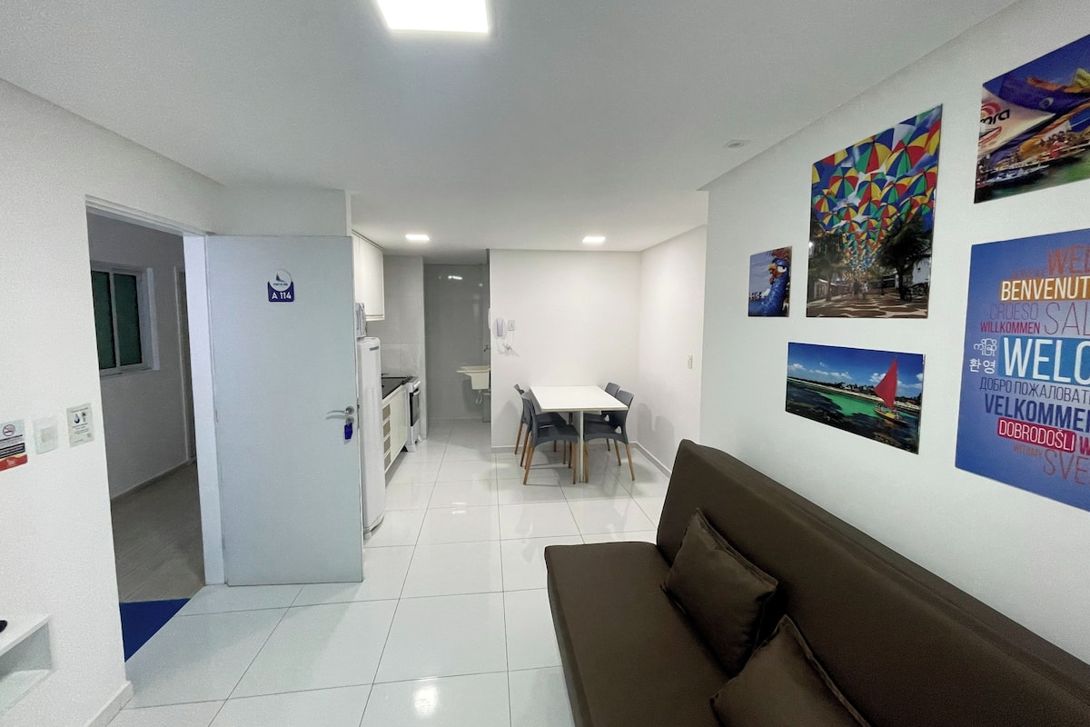 Un moderno vestíbulo de hotel con un comedor, un sofá y una cocina al fondo.