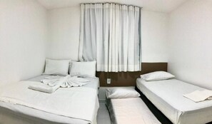 Ein Zimmer mit zwei Betten, einem Fenster mit Vorhängen und einem braunen Kopfteil.