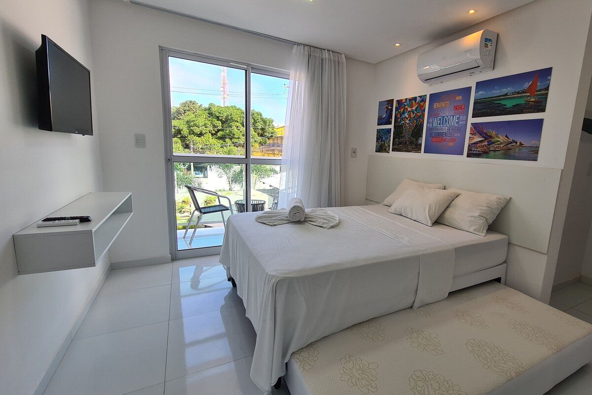 A modern bedroom with a bed, a small desk, and a TV.