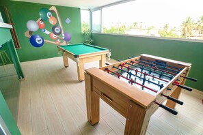 Ein Zimmer mit Kicker-, Billard- und Pooltisch.