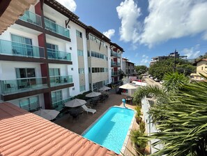 A multi-story hotel with a swimming pool, outdoor seating, and balconies. - Porto Sol Flats by AFT (Ipojuca)