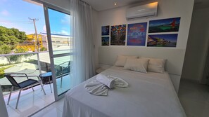 Habitación de hotel con una cama grande, un balcón con una silla y vistas a la ciudad.