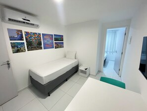 A bedroom with a bed, a small bedside table, and a wall with several posters. - Porto Sol Flats by AFT (Ipojuca)