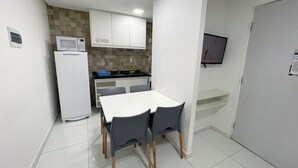 A compact kitchen with white cabinets, a microwave, and a small dining table with chairs. - Porto Sol Flats by AFT (Ipojuca)