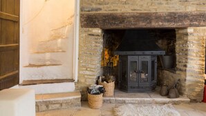 Una chimenea de piedra con puerta de vidrio negro, una cesta tejida y un manto de piel en el suelo.