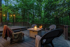 An outdoor deck with a fire feature, seating, and a view of a forested area. - Camp Sasquatch*3B/3BA*PetsOk*Pool (Deep Gap)