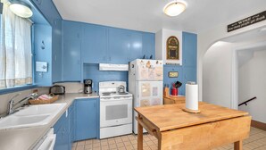 A compact kitchen with blue cabinets, a white stove, and a wooden table. - Spacious Beach Home for the whole family, 2 Blocks to Beach/Seaside Promenade (Seaside)