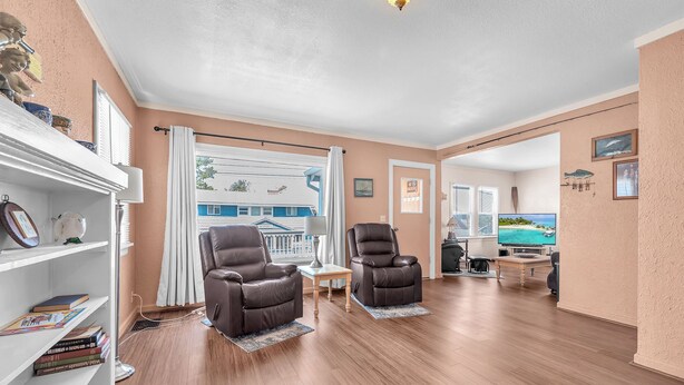 A spacious living room with two leather recliners, a bookshelf, a television, and a view of the ocean through large windows. - Spacious Beach Home for the whole family, 2 Blocks to Beach/Seaside Promenade (Seaside)