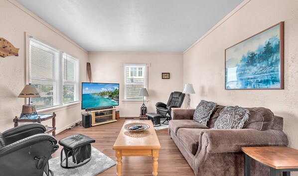 A living room with a TV, leather sofa, and a painting. - Spacious Beach Home for the whole family, 2 Blocks to Beach/Seaside Promenade (Seaside)