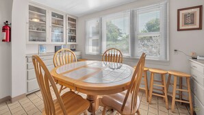 A dining area with a round table, wooden chairs, a white cabinet with glass doors, and a fire extinguisher mounted on the wall. - Spacious Beach Home for the whole family, 2 Blocks to Beach/Seaside Promenade (Seaside)