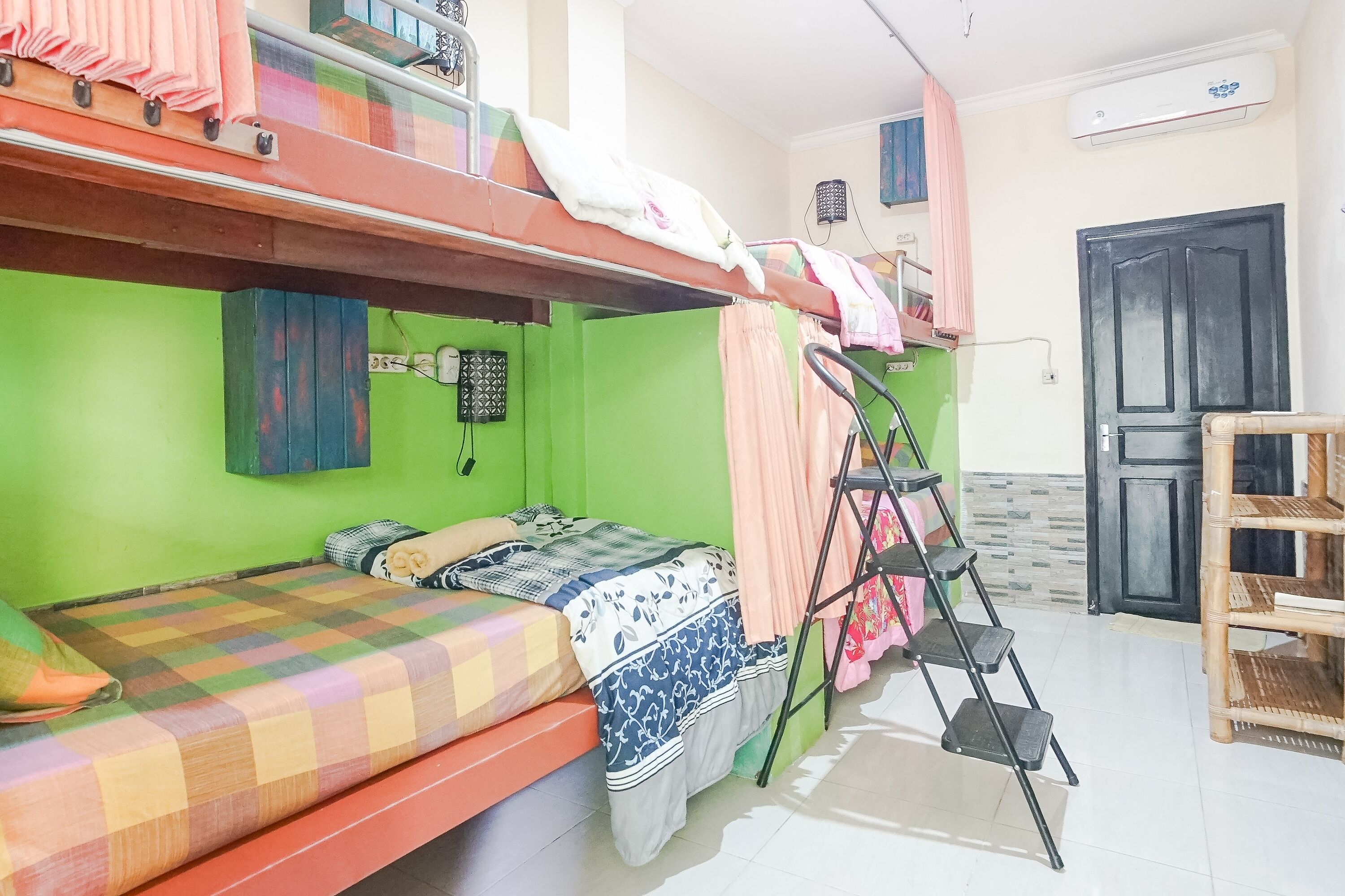 Una camera del dormitorio con letti a castello, una scala, uno scaffale in legno e una porta.