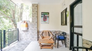 A balcony with a wicker chair, a table, and a blue chair. There is a poster on the wall and a window with a curtain. - Green View Ubud Hostel Bali (Ubud)