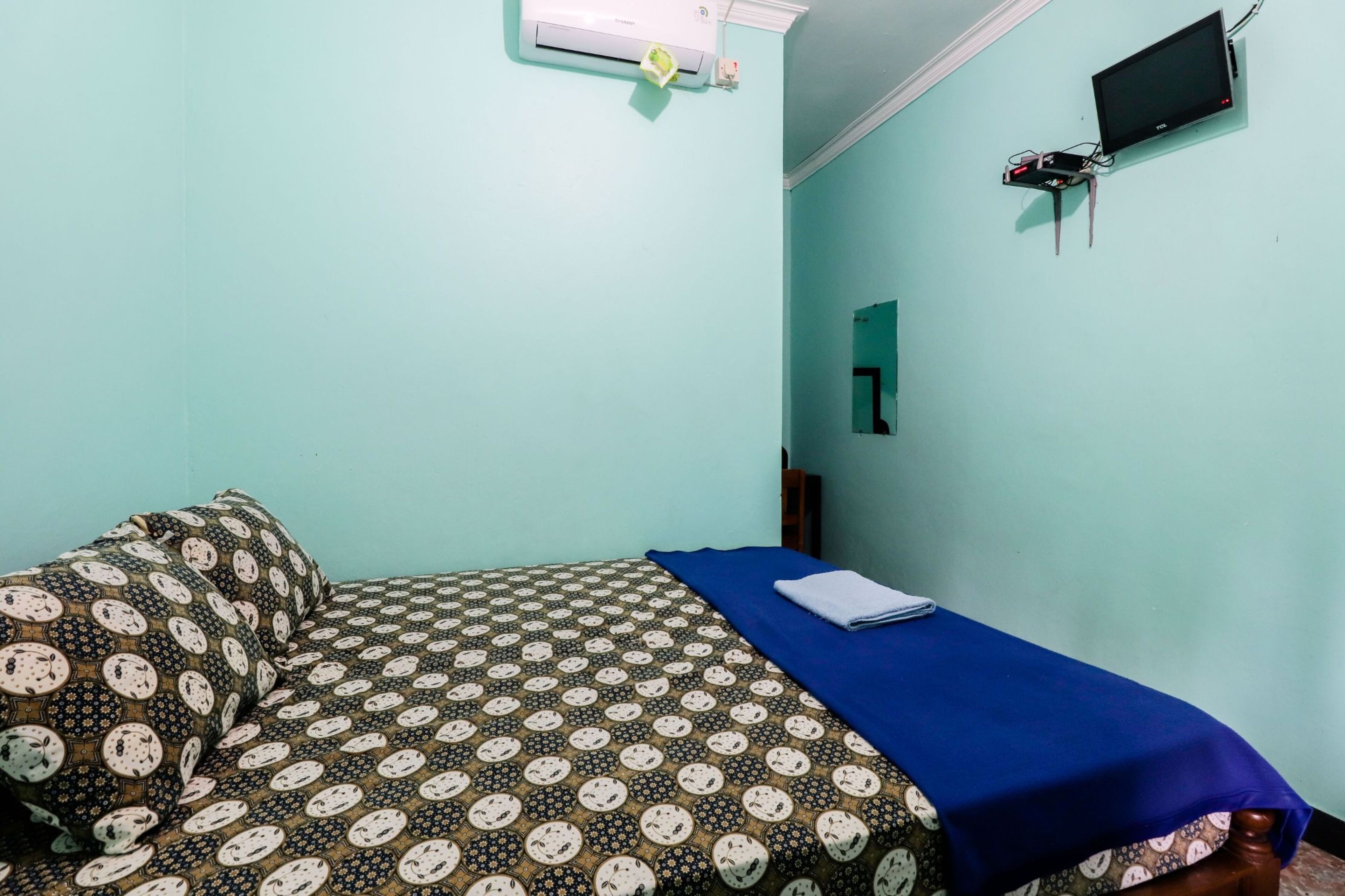Ein Zimmer mit einem Bett, einem flachbildfernseher an der Wand und einer Klimaanlage.