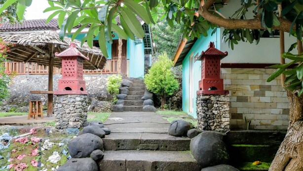 A stone staircase leading to a traditional building with a thatched roof and red lanterns.
