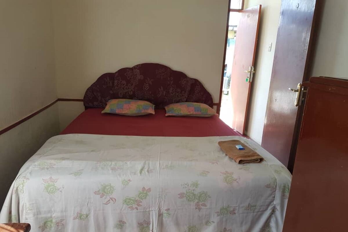 A single bed with a floral bedspread, two pillows, and a folded towel on the bed.