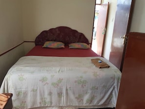 A single bed with a floral bedspread, two pillows, and a folded towel on the bed.