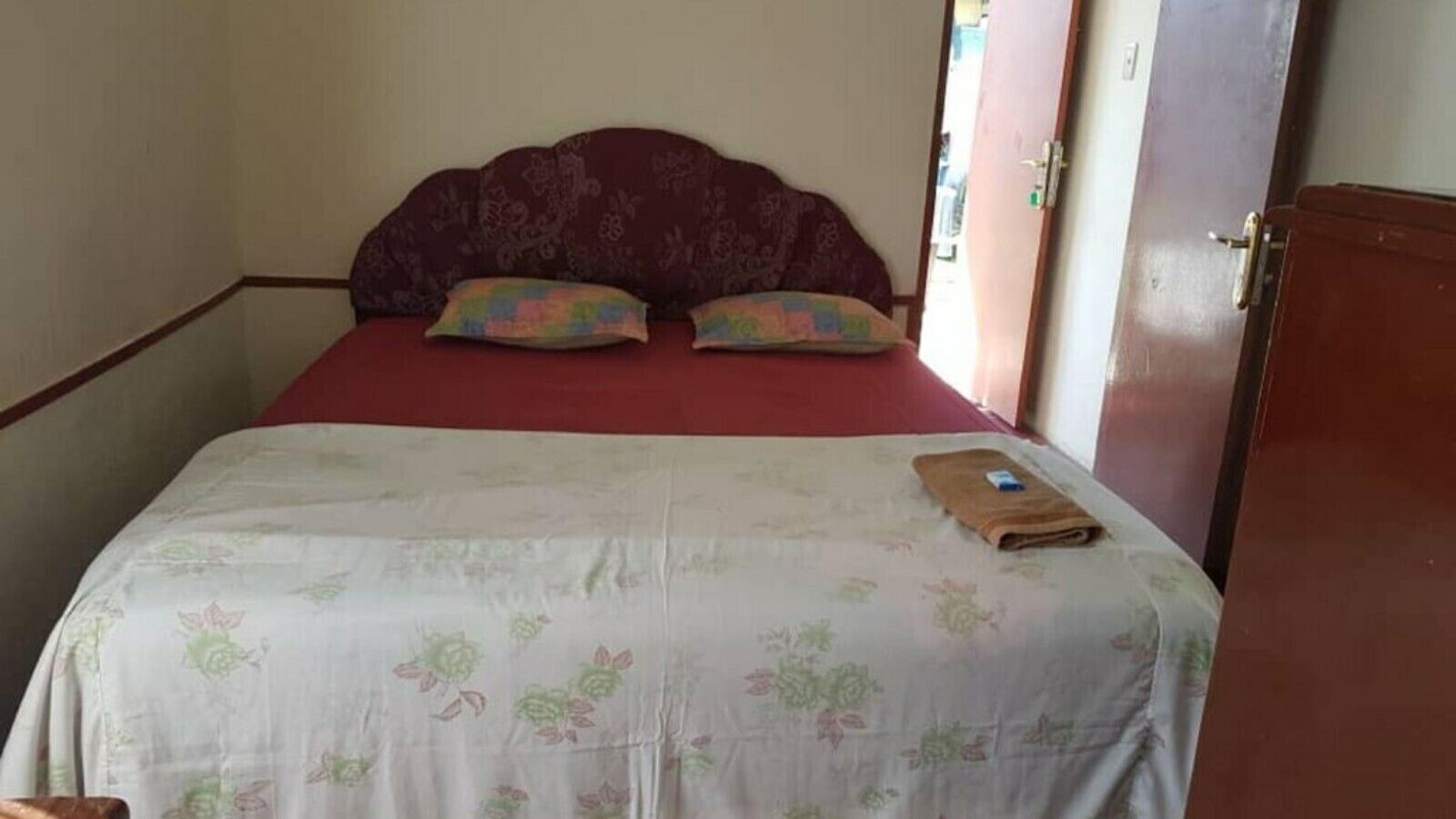 Uma cama de solteiro com colcha floral, duas almofadas e uma toalha dobrada sobre a cama.
