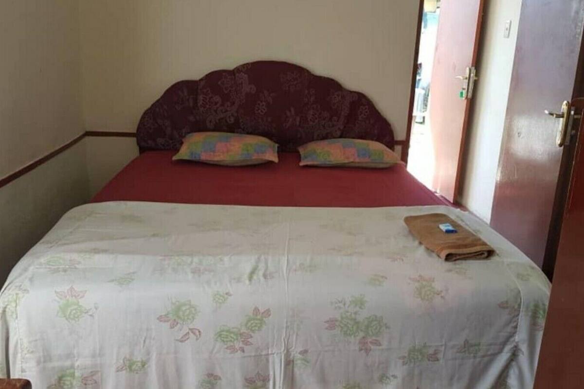 A bed with a floral bedspread, two pillows, and a folded towel.
