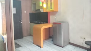 Eine kleine Küche mit Arbeitsplatte, Kühlschrank und Fernseher.