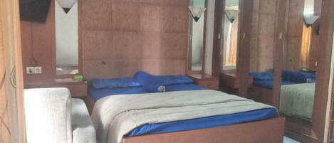 A bedroom with a bed, a chair, and a mirror.