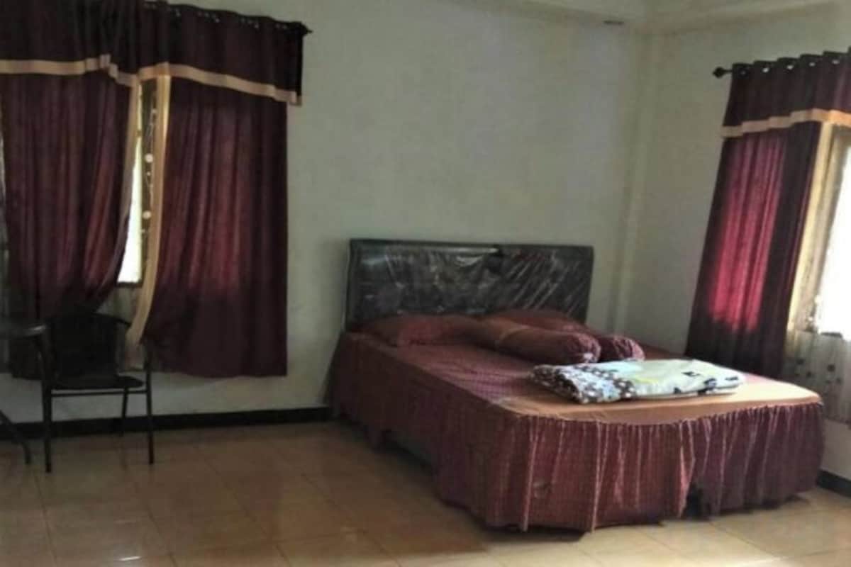 A bedroom with a bed, curtains, and a chair.
