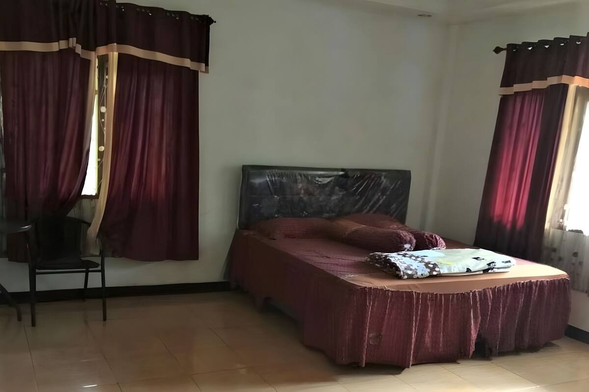 Ein Schlafzimmer mit einem Bett, einem Sessel und Vorhängen.