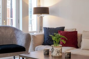 Ein modernes Wohnzimmer mit einer Sofagarnitur, einem Couchtisch, einer Stehlampe und dekorativen Accessoires.