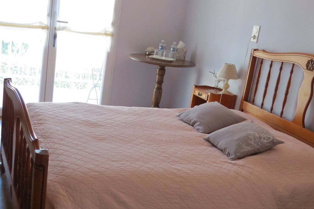 Un dormitorio con una cama, una mesita de noche, una lámpara y una pequeña mesa con objetos encima.