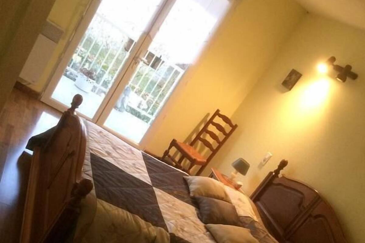 Un dormitorio con una cama de madera, una silla, una mesita de noche y un aplique de pared.