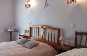 Une chambre à coucher avec une tête de lit en bois, deux tables de chevet avec des lampes, une petite table ronde avec une lampe et un luminaire fixé au mur.