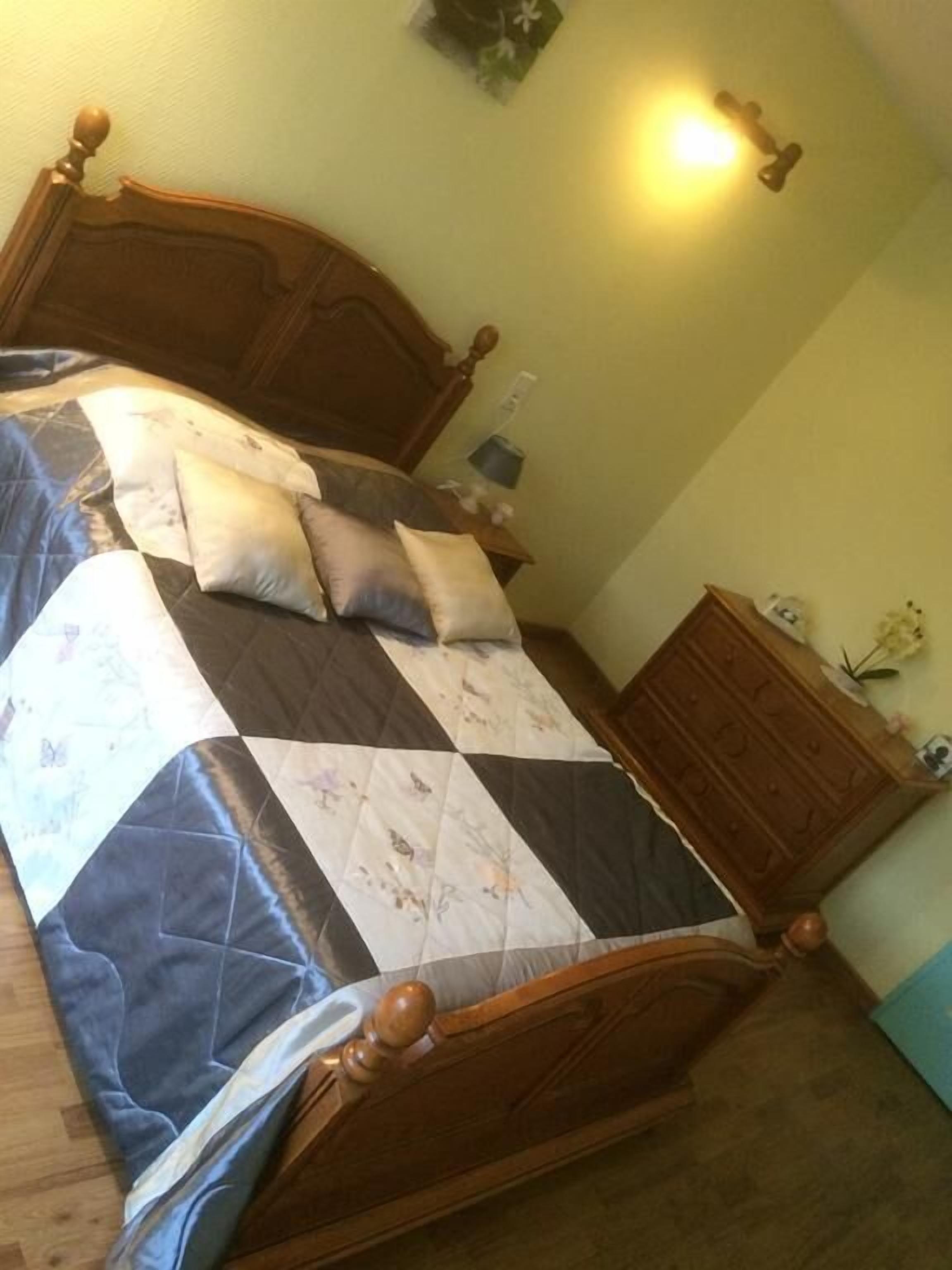 Un dormitorio con una cama de madera, un edredón y una mesita de noche con una lámpara.