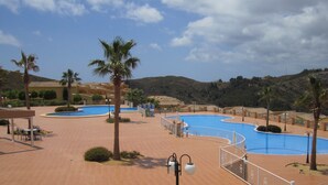 A resort with multiple swimming pools, palm trees, and a tiled walkway. - APARTMENT-COMMUNITY POOL-CUMBRE DEL SOL-CLOSE TO MORAIRA-BEAUTIFUL VIEWS (BENITACHELL)