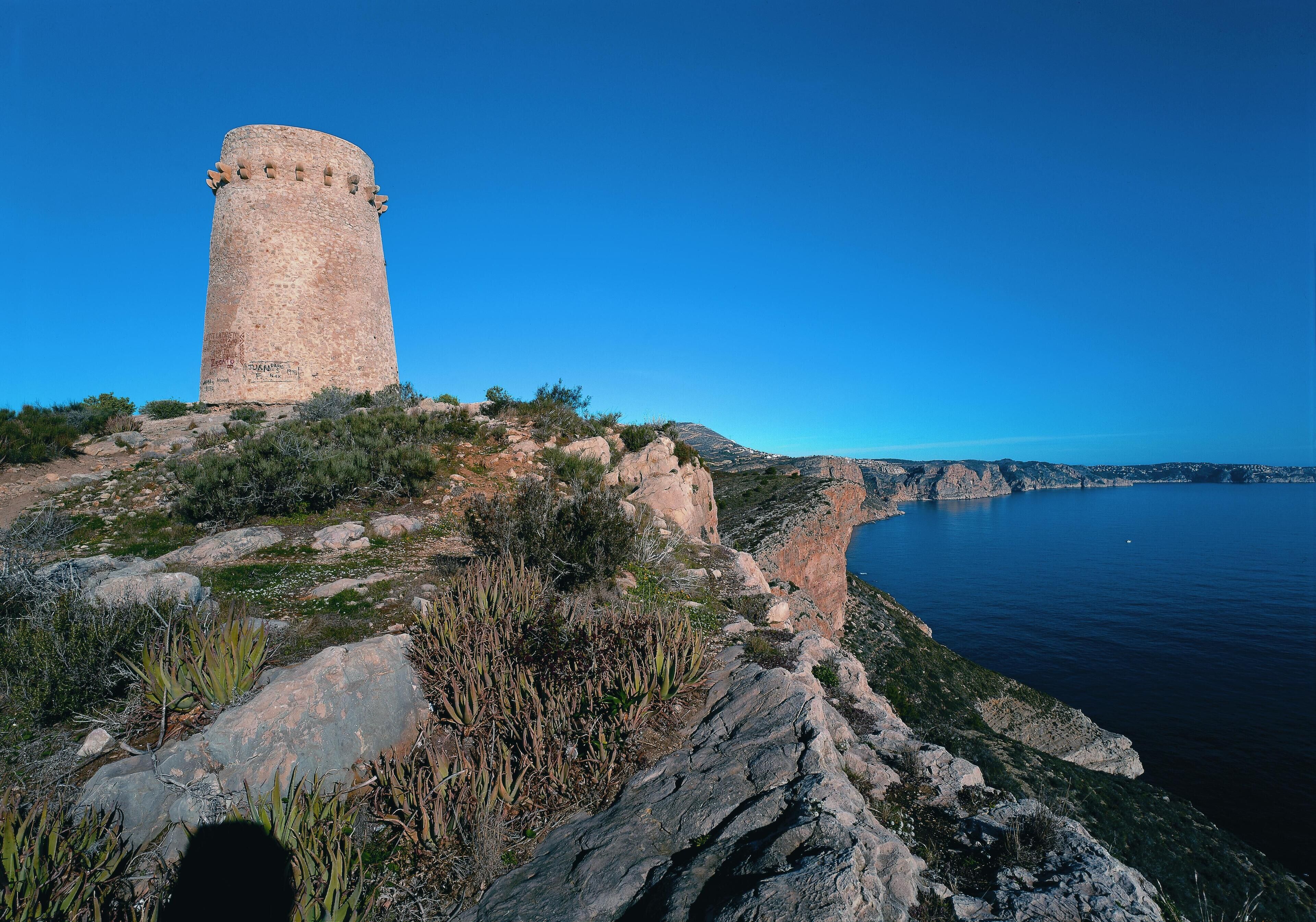 A coastal tower on a rocky outcrop with a clear view of the sea.