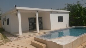 A modern house with a swimming pool, a covered patio, and a gated entrance.