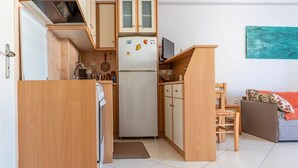 Une cuisine compacte dotée de meubles en bois, d’un réfrigérateur, d’un four à micro-ondes et d’un coin repas avec une chaise et une table.