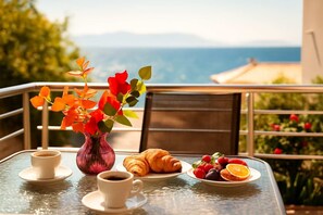 A table with a vase of flowers, croissants, and fruit on a balcony overlooking a scenic view. - Seaside Getaway - Aelia Villa's Dreamy Paradise (Petalidi)