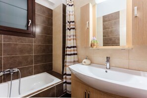 A bathroom with a bathtub, a sink, a mirror, and a shower curtain. - Seaside Getaway - Aelia Villa's Dreamy Paradise (Petalidi)