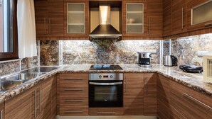 Una cocina con armarios de madera, un lavamanos de acero inoxidable, horno empotrado y encimera de granito.