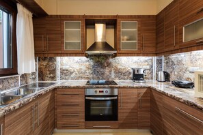 A kitchen with wooden cabinets, a stainless steel sink, a built-in oven, and a granite countertop.