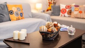 En hyggelig stue med sofa, sofabord og dekorative genstande samt en lampe.