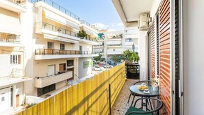 En balkon med et gult hegn, et bord med stole og udsigt til nabobygninger.