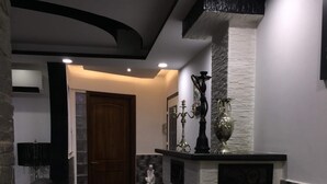 A modern hallway with a stone accent wall, a dark wood floor, and a dark leather sofa. - Rental apartment close to all services. (Bouzareah)