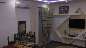 A bedroom with a bed, a desk, a chair, a TV, and a ceiling light. - Rental apartment close to all services. (Bouzareah)