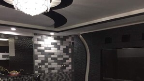A modern living room with a black leather sofa, a glass coffee table, and a large flat-screen TV mounted on the wall. - Rental apartment close to all services. (Bouzareah)