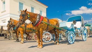 A horse-drawn carriage parked in front of a building with a white facade and blue windows. - Thalassa, Return To Timeless Spetses (Spetes)