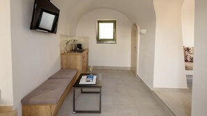 A modern, minimalist interior with a built-in kitchen, a seating area, and a television mounted on the wall.