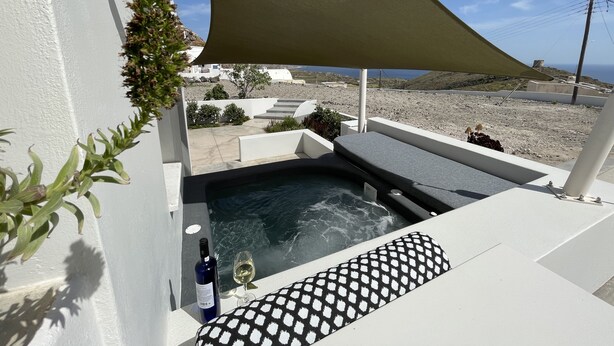 A balcony with a hot tub, a bottle of wine, and a glass on the edge.