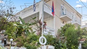 En bygning med balkon, trapper op til indgangen og et flagstang med flag.