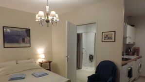 A hotel room with a bed, a chair, a desk, a sink, and a shower. - Independent studio 25m² 800 m from the sea (Anneville-sur-Mer)