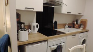 A compact kitchen with a toaster, kettle, sink, oven, and a small refrigerator. - Independent studio 25m² 800 m from the sea (Anneville-sur-Mer)